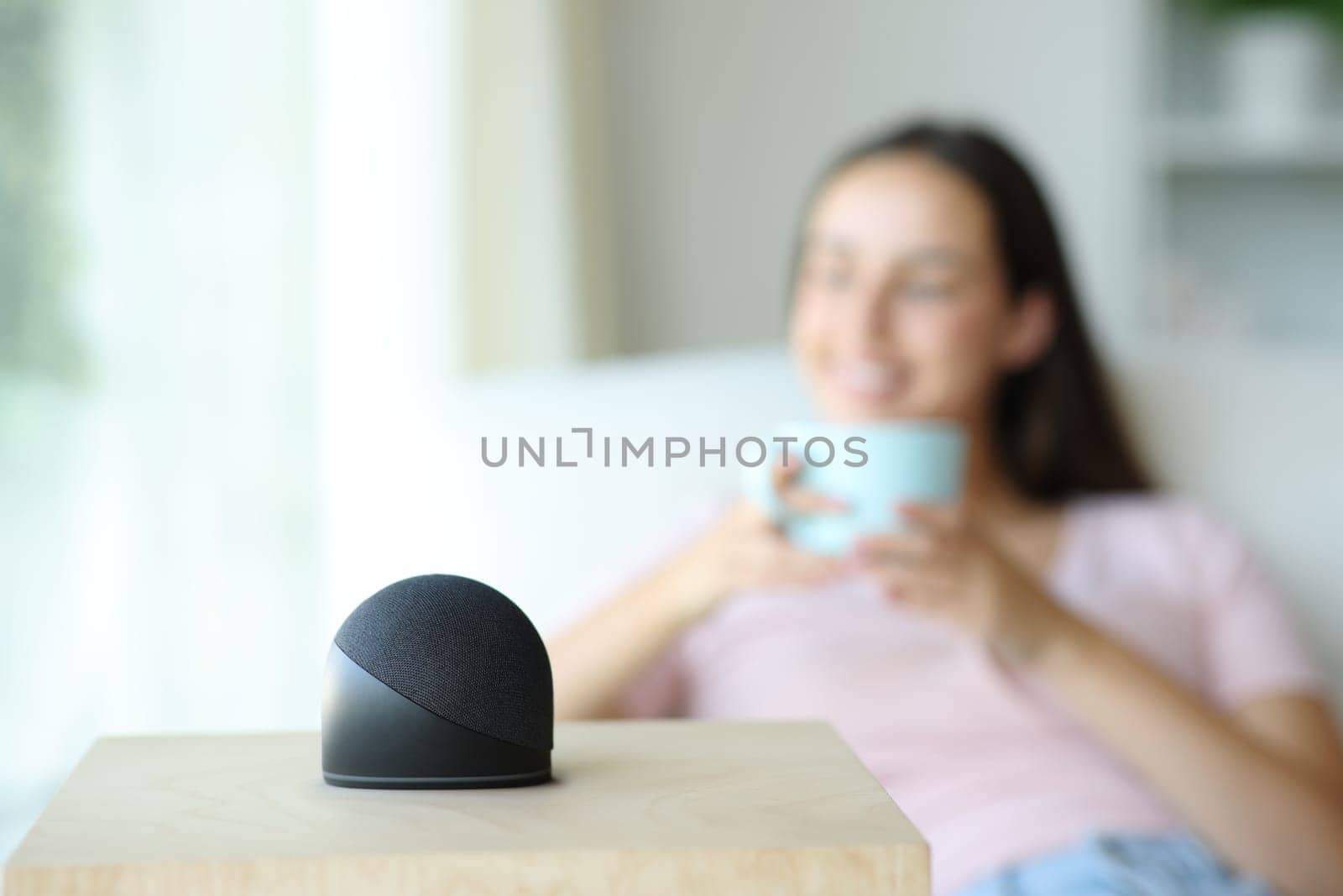 Happy woman is relaxing and drinking coffee with smart speaker at home