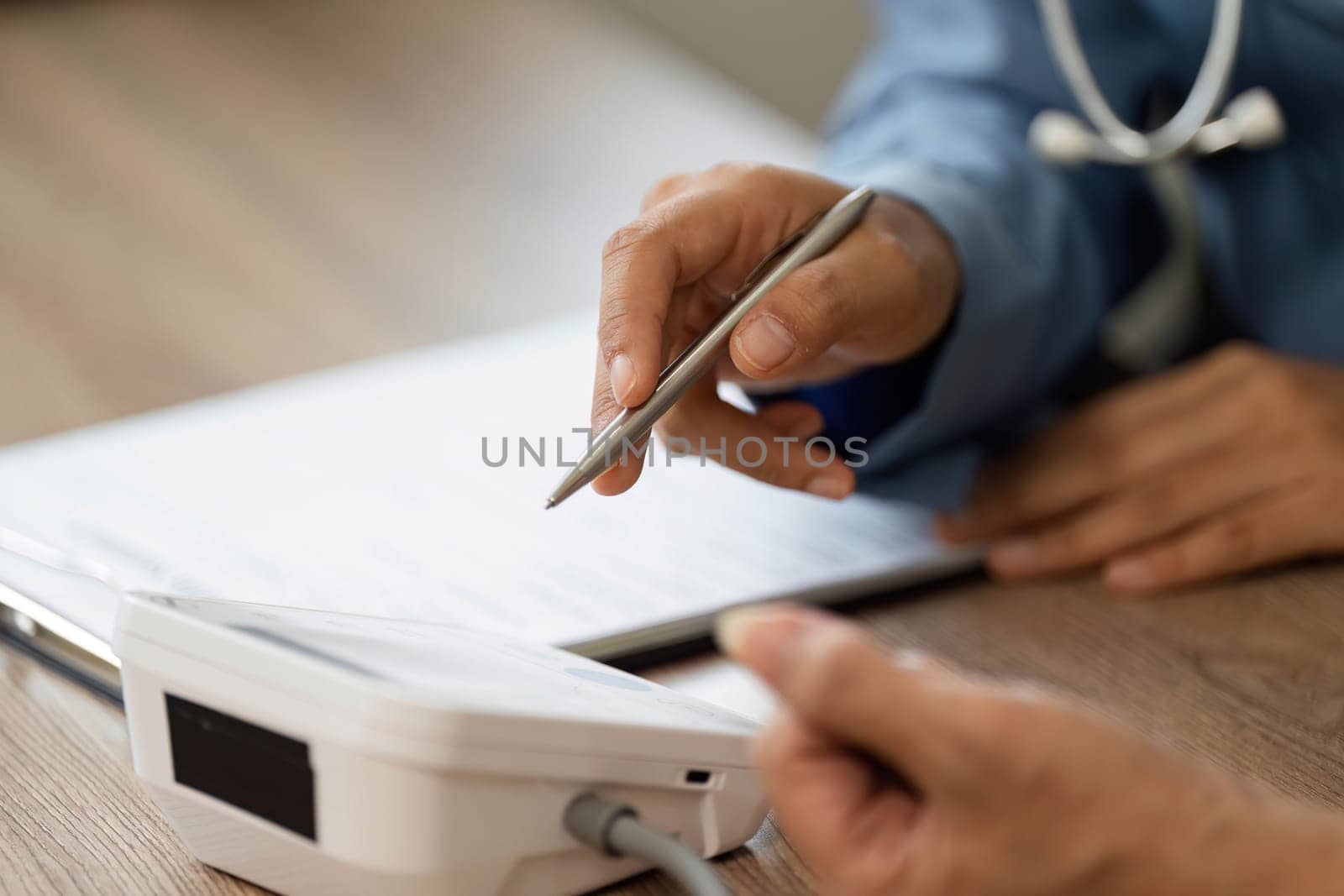 In a clinical setting, a nurse points to a health monitor and explains the medical data to a patient, ensuring they understand the importance of their results.