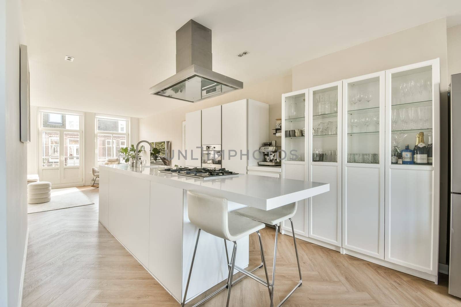 A sleek and contemporary kitchen featuring an open layout with white cabinetry, an island, and large windows for natural light. Ideal for modern living spaces.