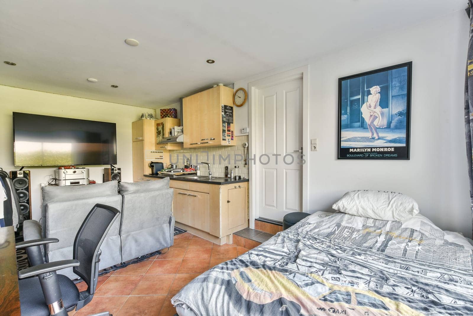 A bright and comfortable living space featuring a kitchenette, contemporary furniture, and a large television, ideal for relaxation and entertainment.