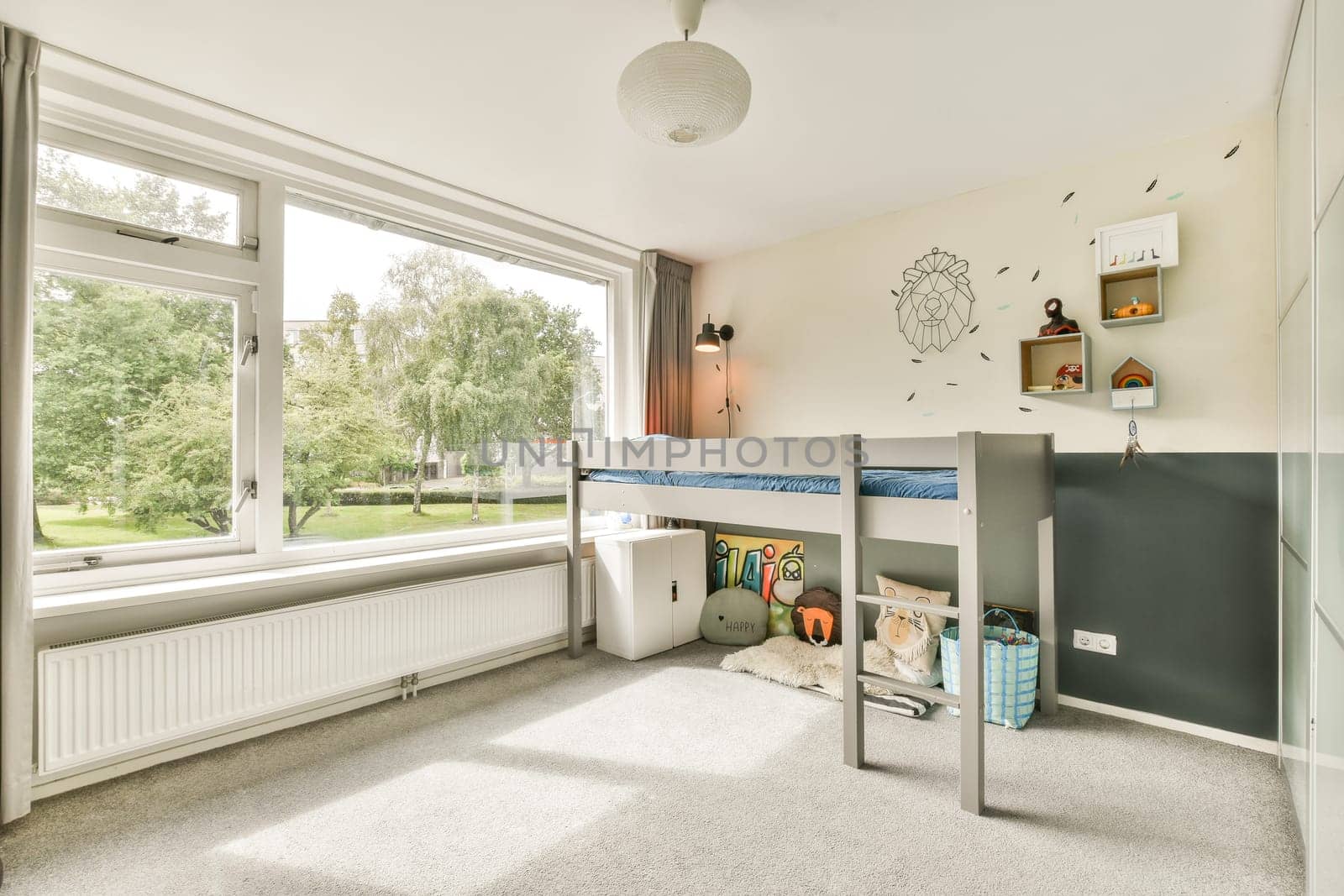 A well-lit and organized children bedroom featuring a loft bed, playful decor, and ample natural light streaming through large windows.