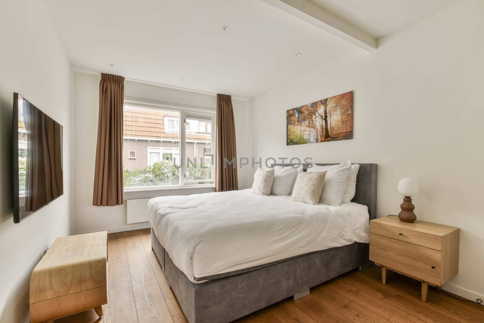 A sleek, modern bedroom featuring a cozy bed, soft textiles, and elegant decor. Natural light spills in from the window, enhancing the serene ambiance.