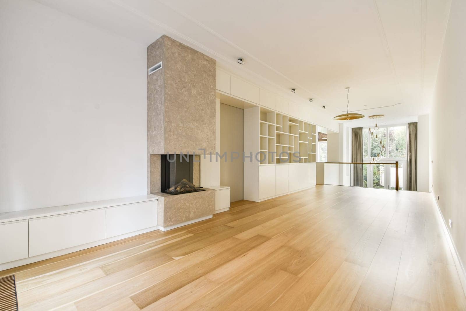 A spacious, minimalist interior featuring a light wooden floor, elegant decor, and a stylish fireplace. The room exudes tranquility and modernity.