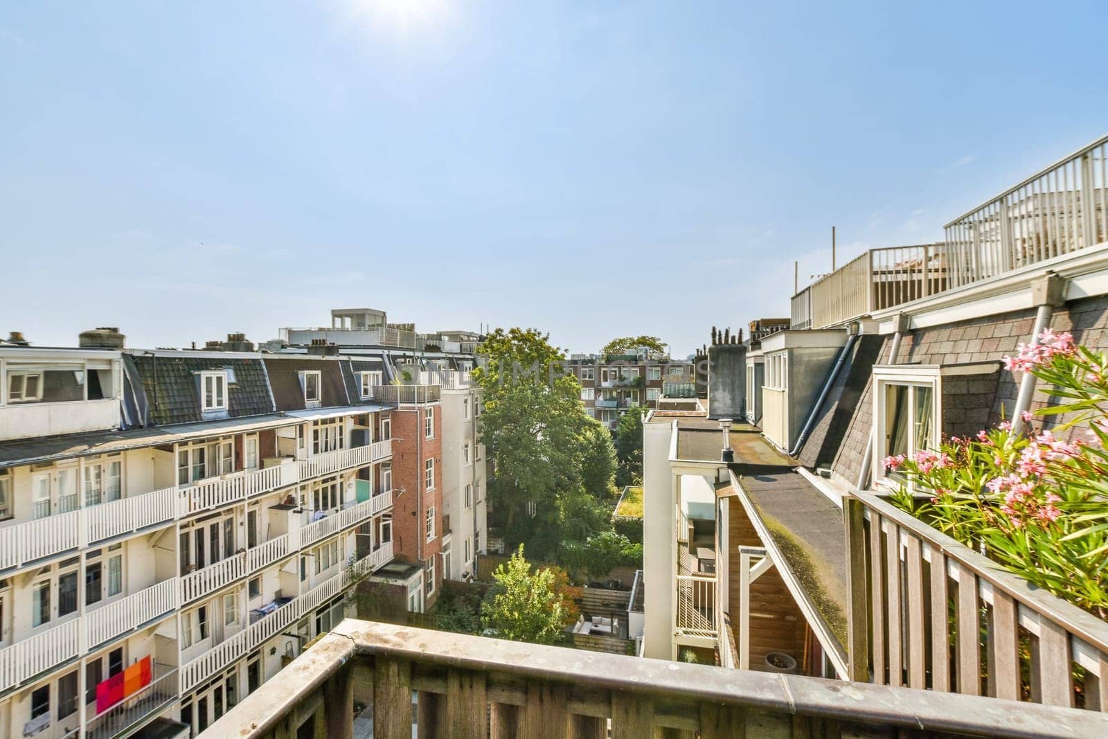 Overlooking an urban landscape, this image features a mix of residential buildings and greenery visible from a balcony, reflecting a vibrant city life.