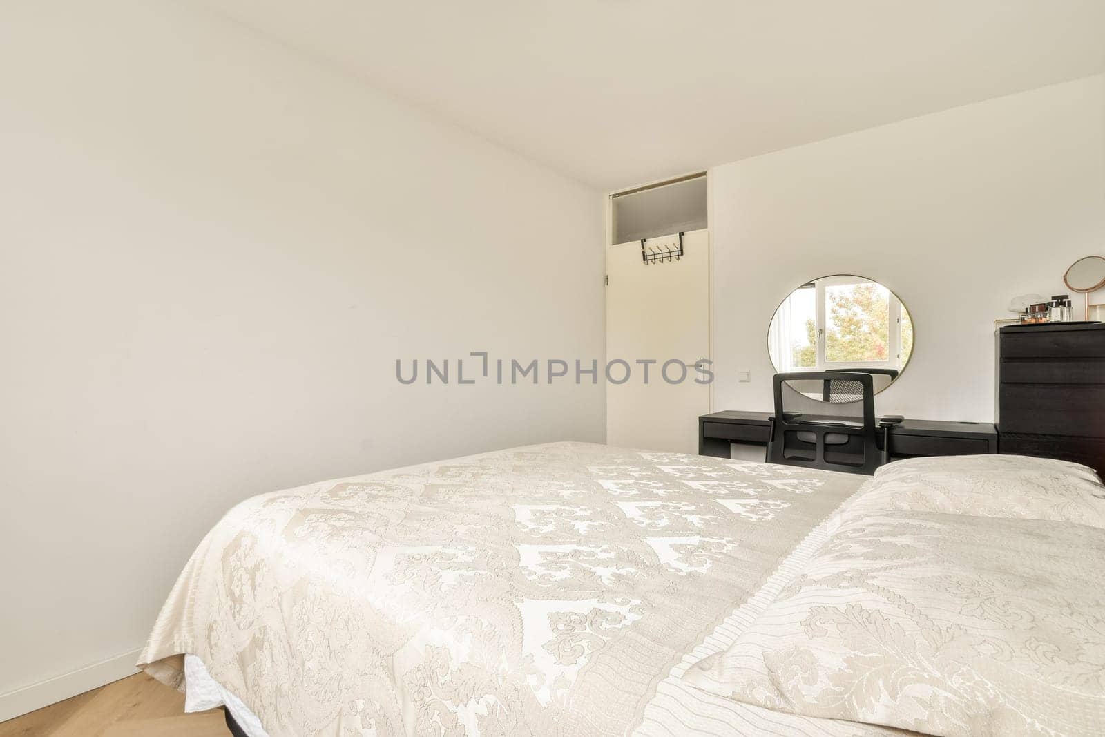 A spacious modern bedroom featuring a light color palette, elegant decor, and minimalistic furniture that enhances the room's tranquility.