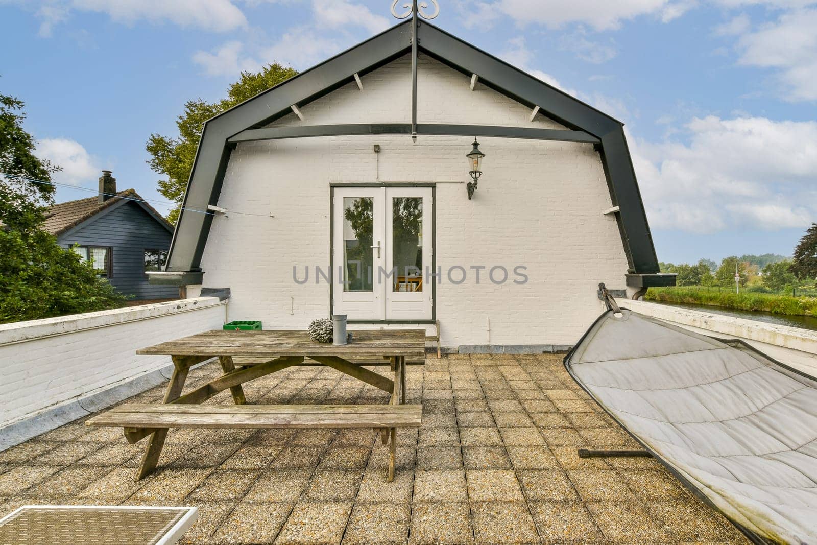A picturesque rooftop terrace featuring a table, chair, and decorative elements, set against a serene backdrop of nature and clouds.