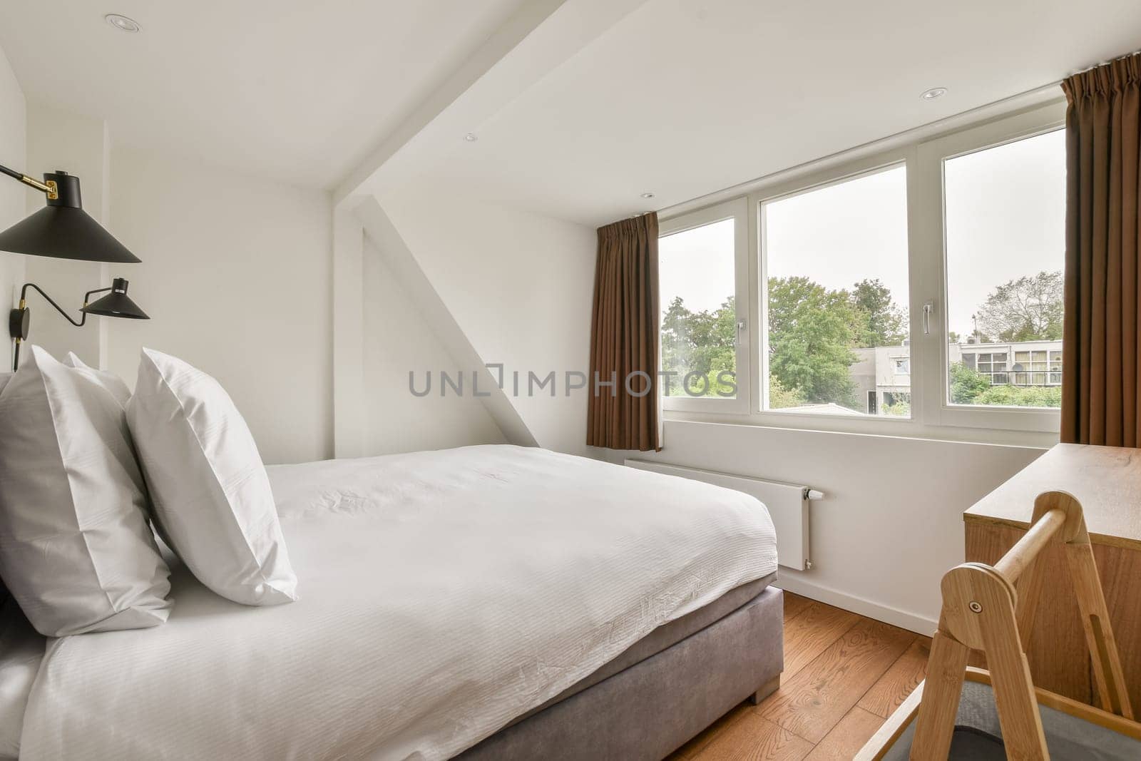 Stylish bedroom featuring large windows, soft bedding, and neutral tones, creating a serene and inviting atmosphere for relaxation.