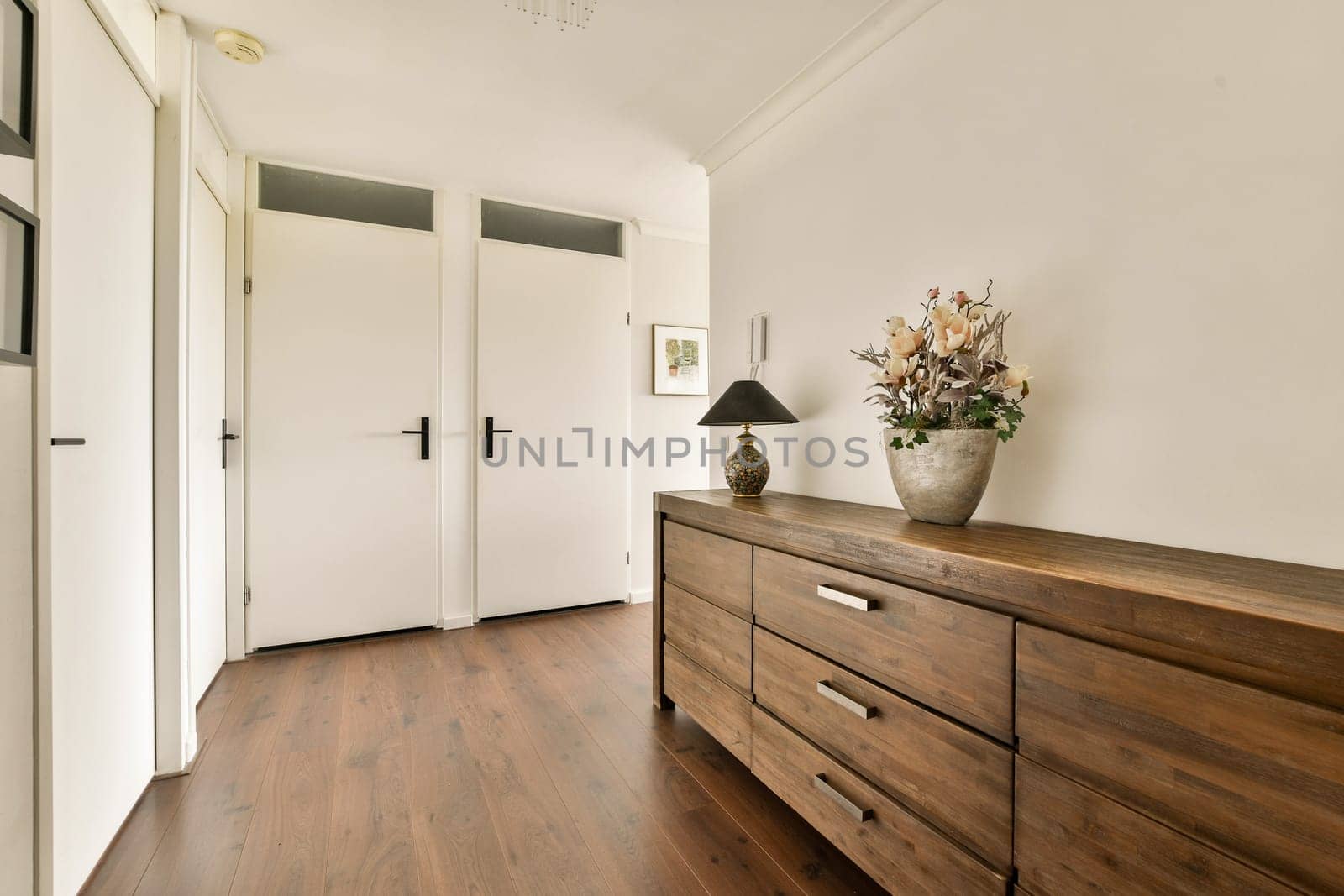 A well-lit hallway showcases stylish wooden furniture and decorative elements, creating a warm and inviting atmosphere with a minimalist design.