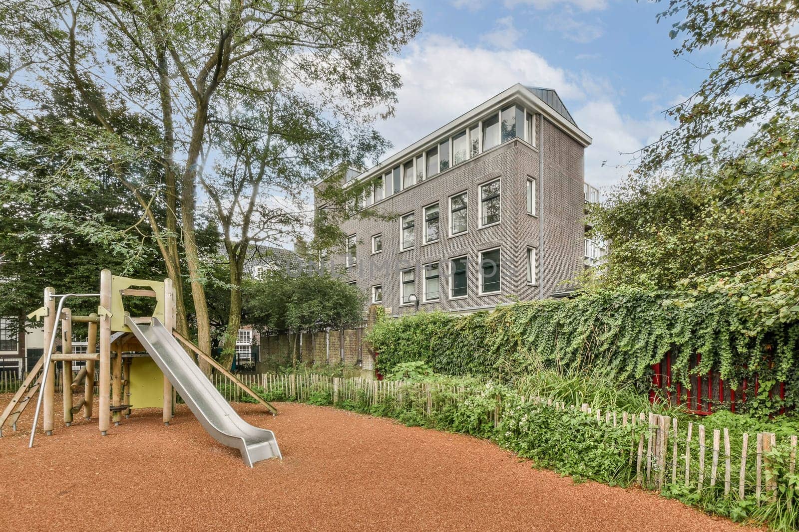 A vibrant playground featuring a slide nestled within lush greenery and a contemporary building in the background, creating an inviting space for children.