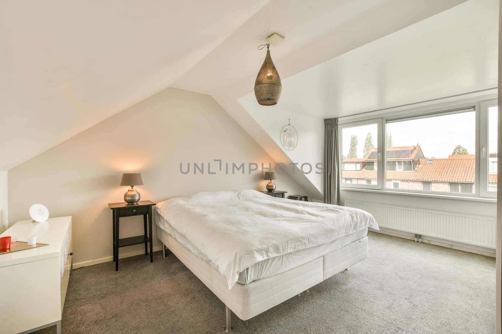 A stylish, well-lit bedroom featuring a comfortable bed, bedside table, and a large window with a scenic view, promoting a serene atmosphere.