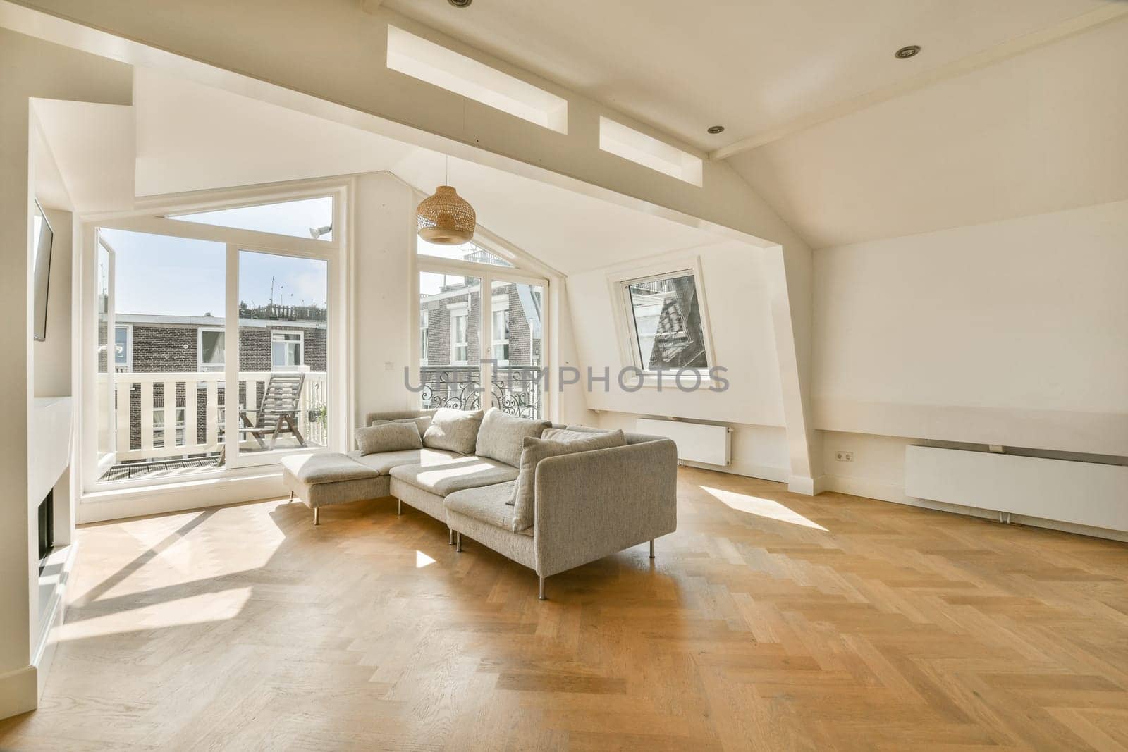 A spacious modern living room featuring ample natural light, stylish decor, a comfortable sofa, and large windows leading to a balcony, showcasing contemporary design.