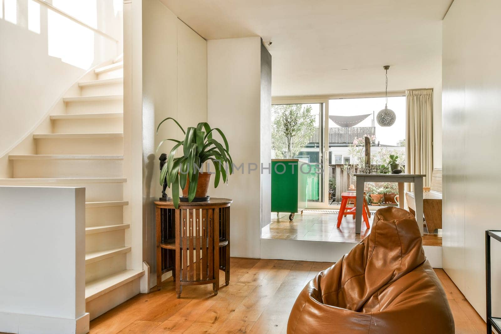 A stylish modern indoor living space featuring natural light, wooden flooring, and decorative plants that enhance the cozy ambiance.