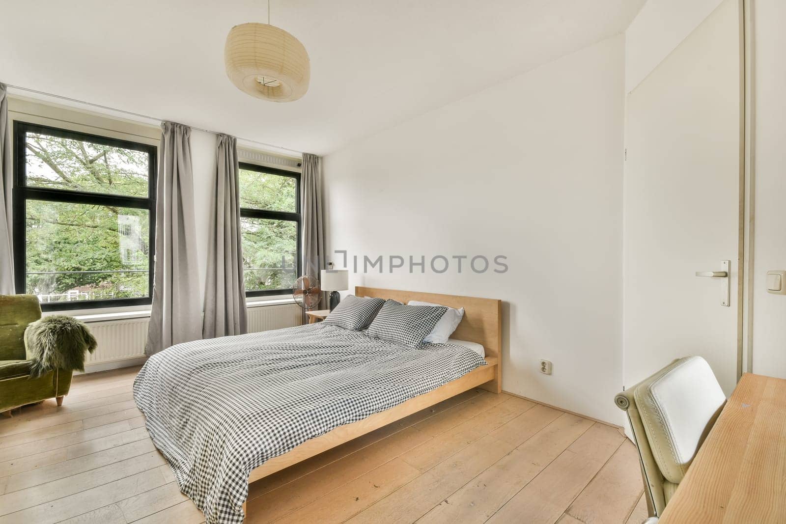 A serene minimalist bedroom featuring large windows that bring in natural light, adorned with simple furnishings and a calming atmosphere.