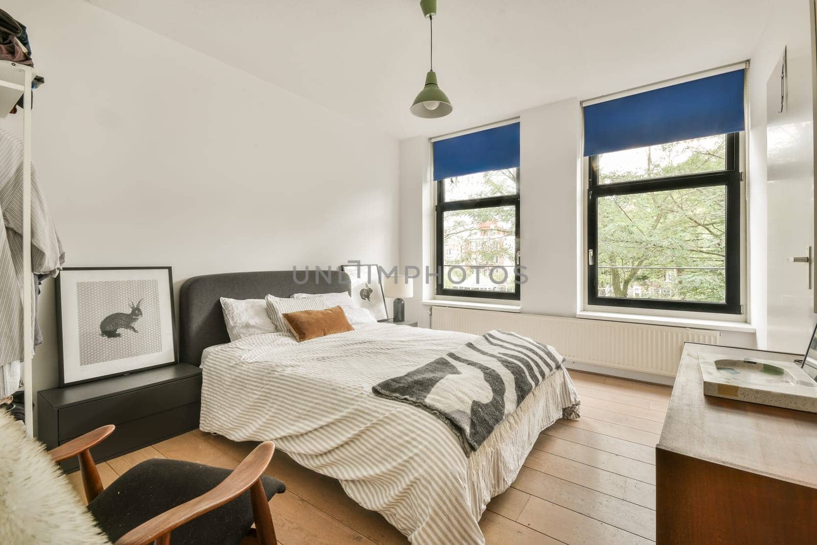 A well-designed modern bedroom featuring natural light from large windows, neutral colors, and minimalist decor elements for a serene atmosphere.