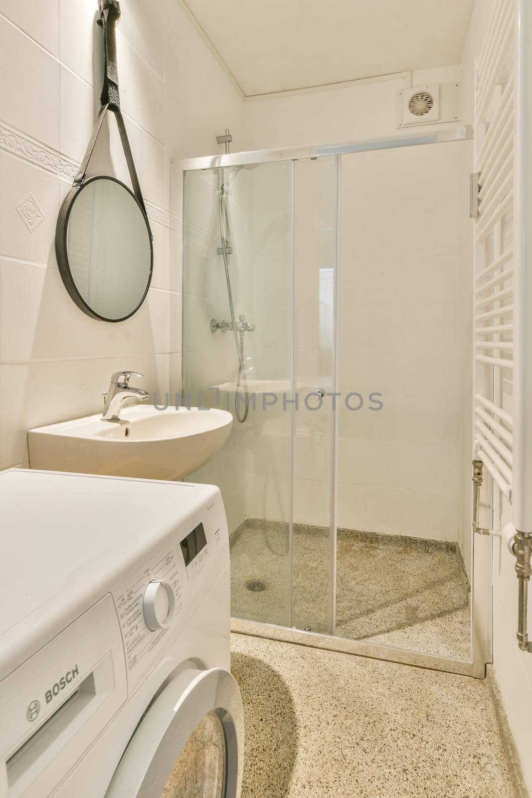 Featuring a sleek design, this space combines a shower area, sink, and a washing machine, ensuring practicality and style in a modern bathroom setup.