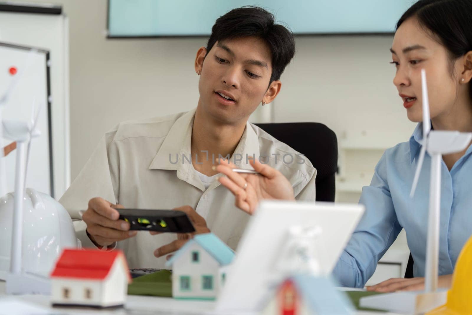 Two young professionals exchange ideas and technologies to enhance sustainable construction practices, demonstrating innovative tools and commitment to ESG goals.