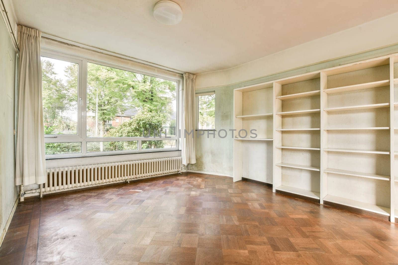 A bright and airy empty room showcasing large windows and wooden flooring. The space is perfect for creative ideas and design transformations.
