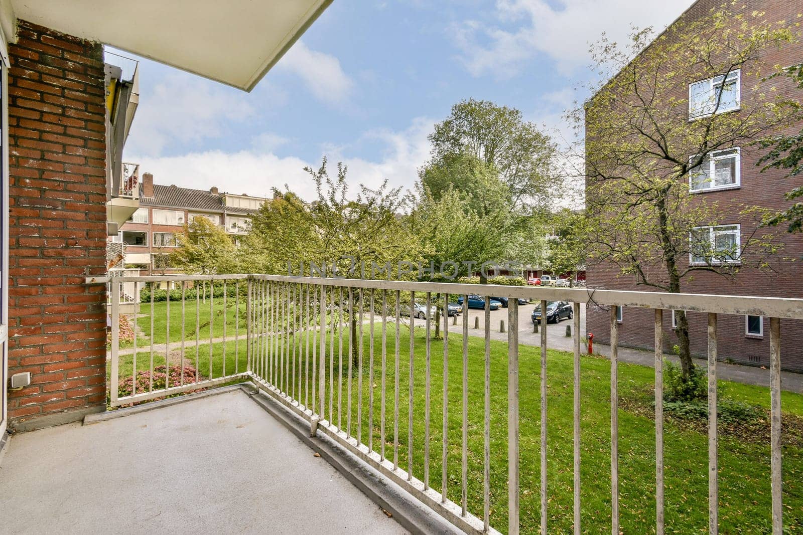 A serene view from a modern apartment balcony overlooking lush greenery, providing a refreshing outdoor space amid an urban environment.