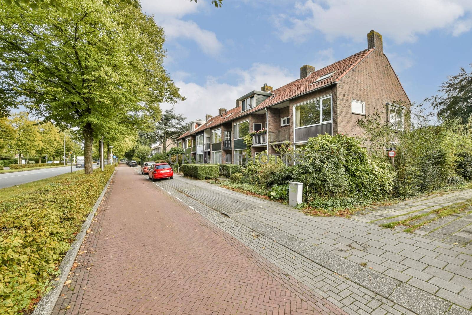 An inviting urban street scene lined with trees and residential buildings, showcasing a blend of nature and architecture.