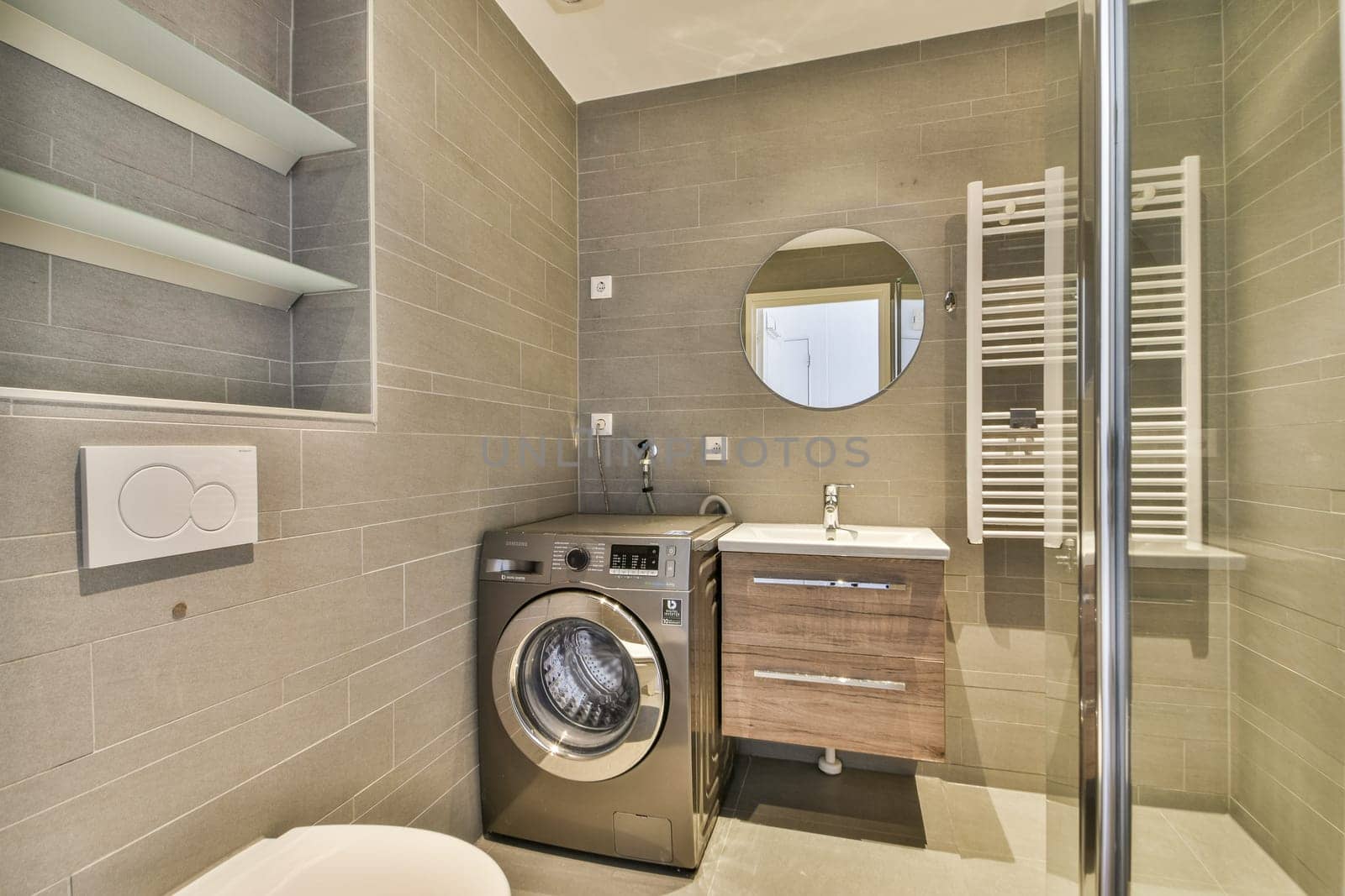 A sleek modern bathroom featuring a combination of grey tiles, a washing machine, and stylish fixtures, enhancing the contemporary home aesthetic.