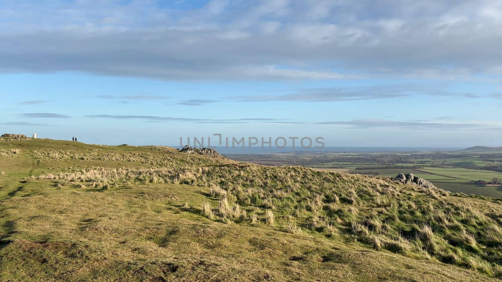 View from the summit of Traprain Law in East Lothian, Scotland, overlooking the surrounding countryside and the sea, under a partly cloudy sky - Nr Haddington, UK