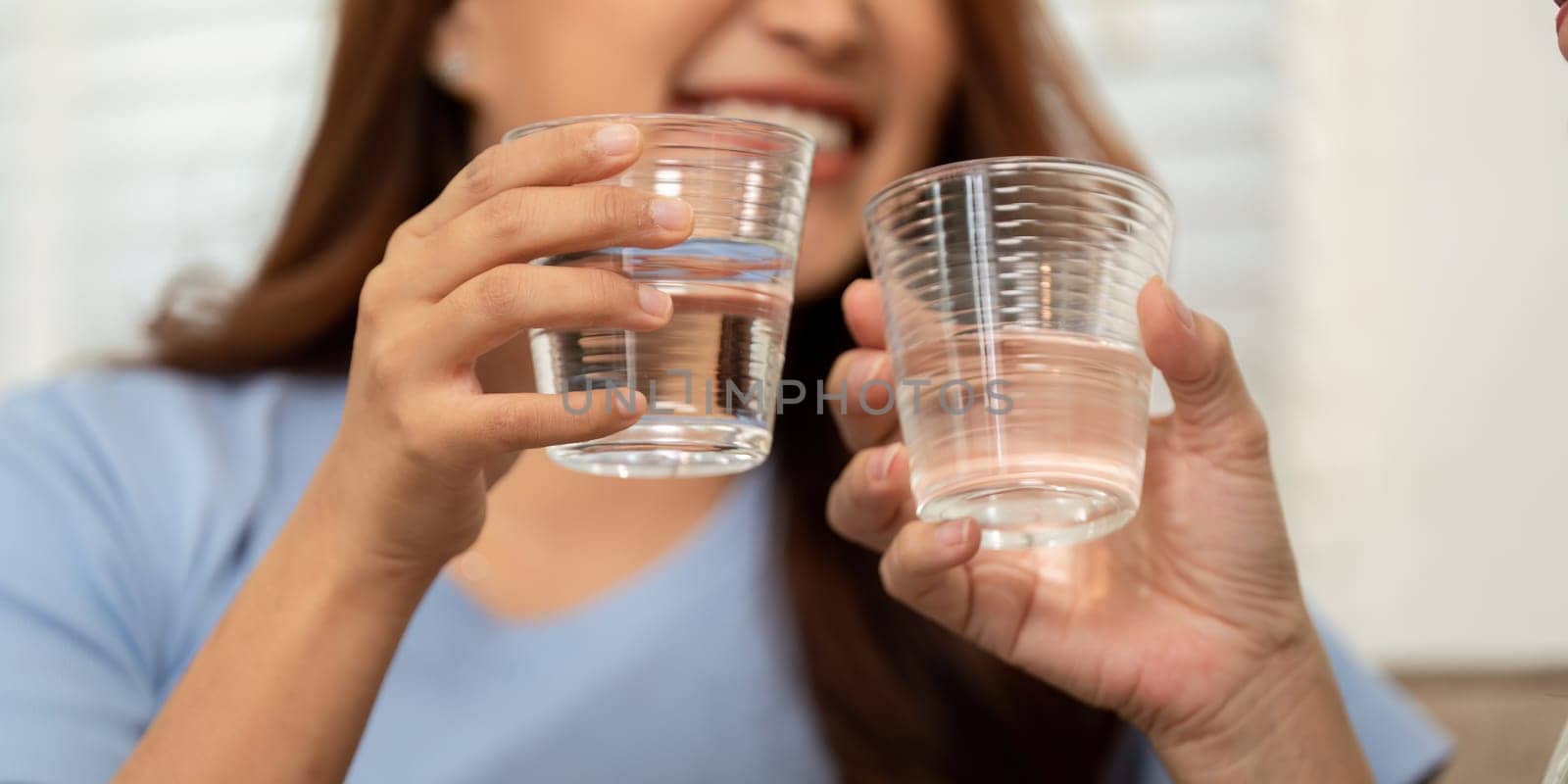 A joyful moment captured between a mother and her child as they raise their glasses of water, emphasizing the significance of hydration and health in their daily lives.