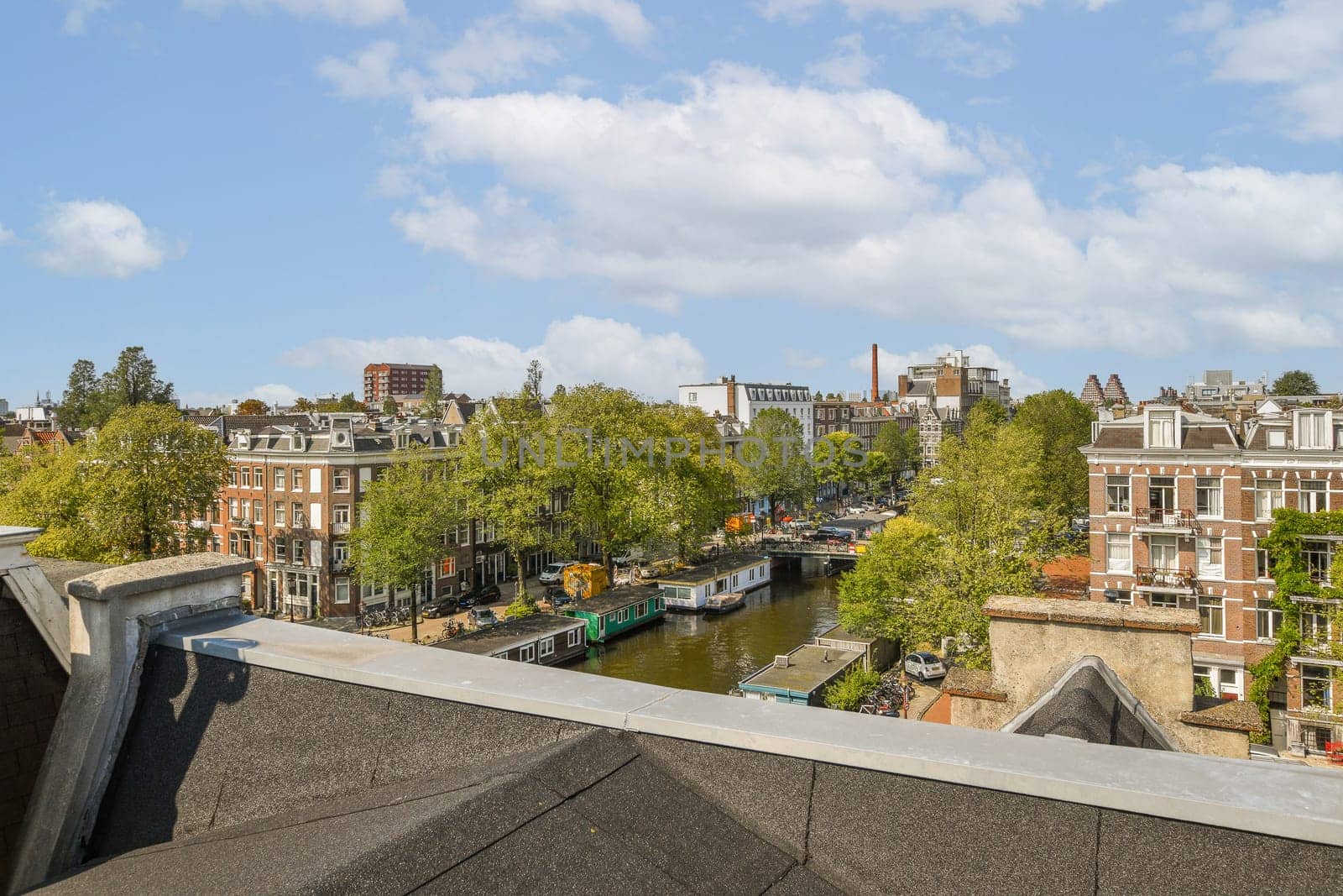 The image showcases a picturesque aerial view of Amsterdam, featuring its iconic canals, lush greenery, and charming historic architecture.