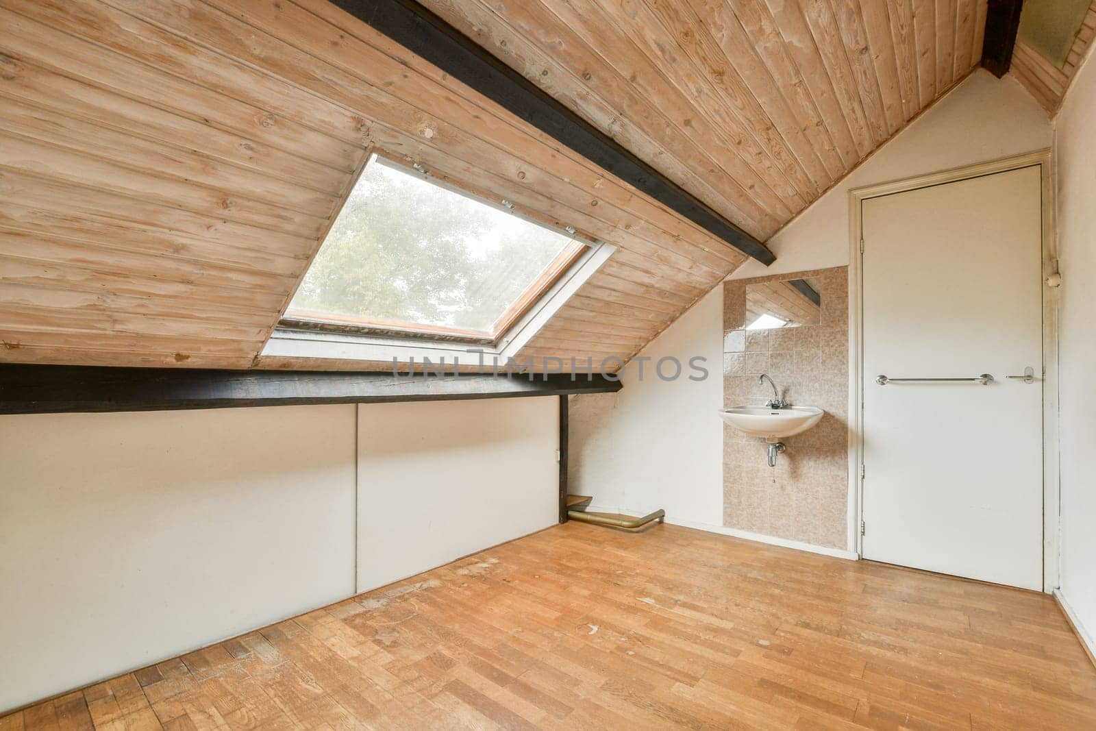 A spacious modern loft interior featuring wooden beams and large windows that allow natural light to illuminate the room, creating a warm and inviting atmosphere.