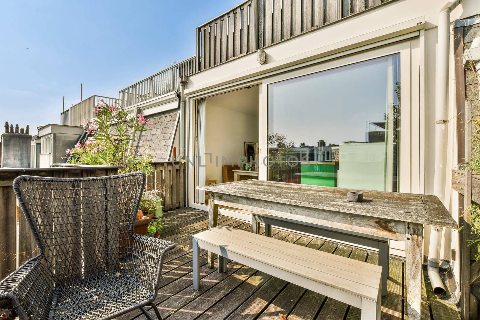 A stylish balcony featuring wooden seating and planters, perfect for relaxation under the clear sky. The modern design offers a cozy atmosphere.