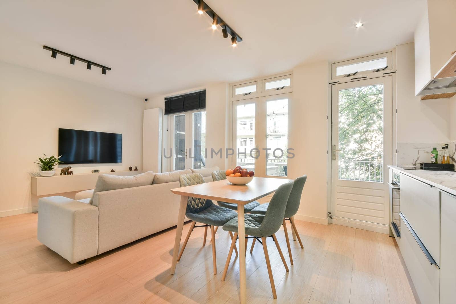 A stylish living room featuring a cozy sofa, a dining table, and large windows that allow plenty of natural light, creating an inviting atmosphere.