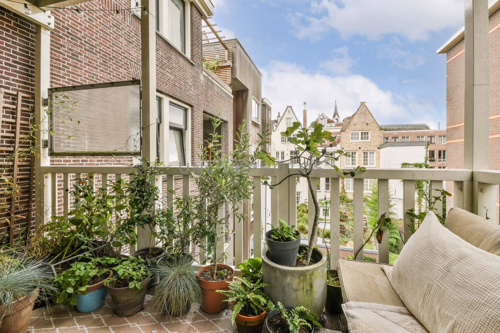 A view of a quaint balcony adorned with various potted plants. The urban background features charming architecture, adding to the serene atmosphere of the space.