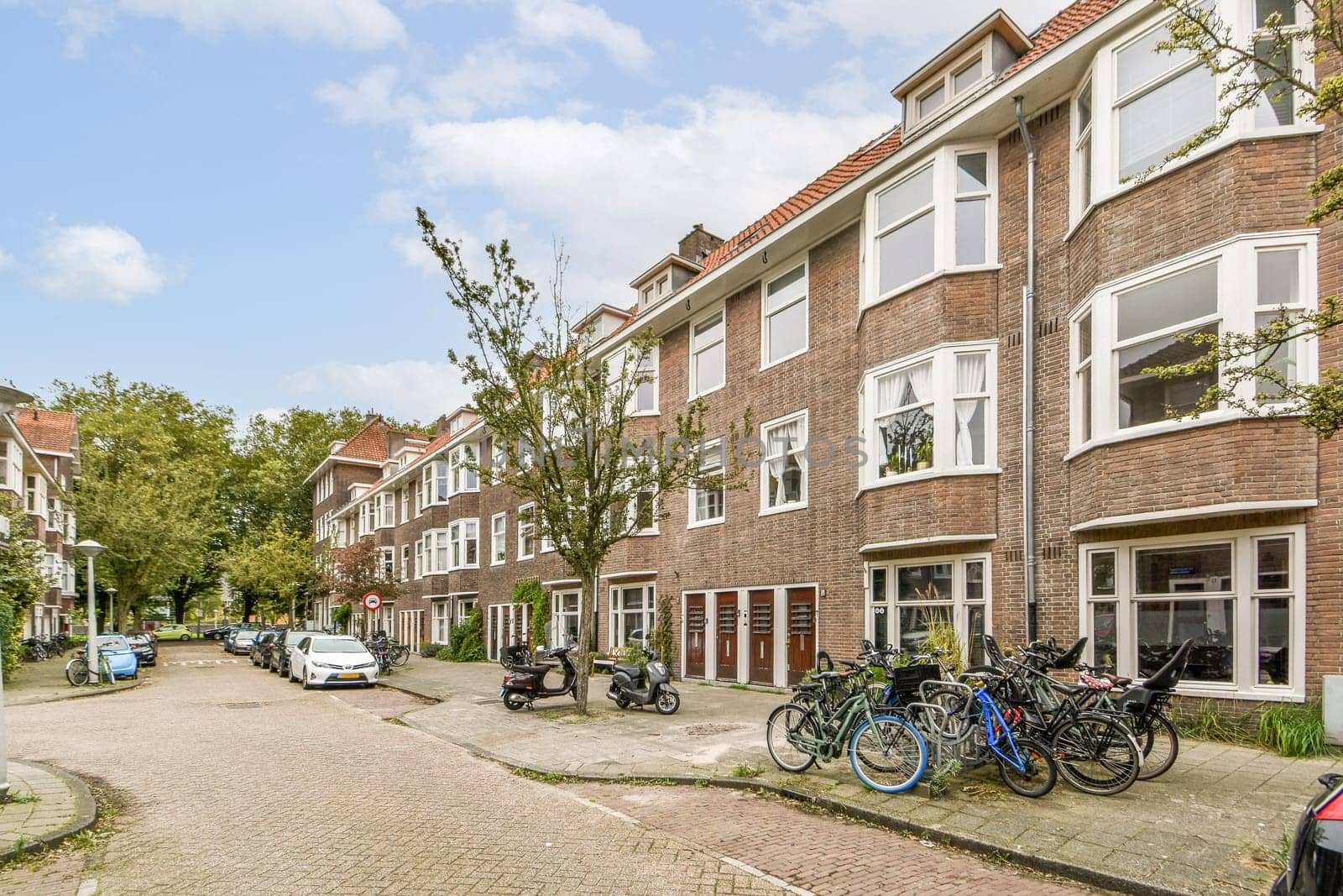 A picturesque view of a charming residential street lined with classic brick buildings and bicycles parked along the road, surrounded by trees.
