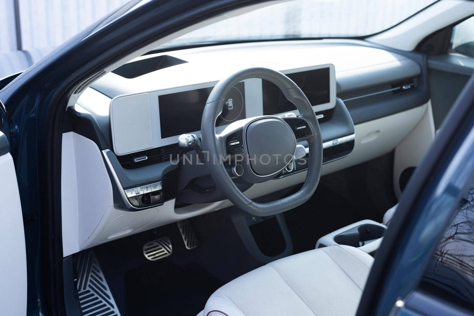 Steering wheel of a electric vehicle, interior cockpit, electric buttons, digital speedometer, front seats, textile, windows, console, gear shift. Car dashboard with a digital touchscreen.