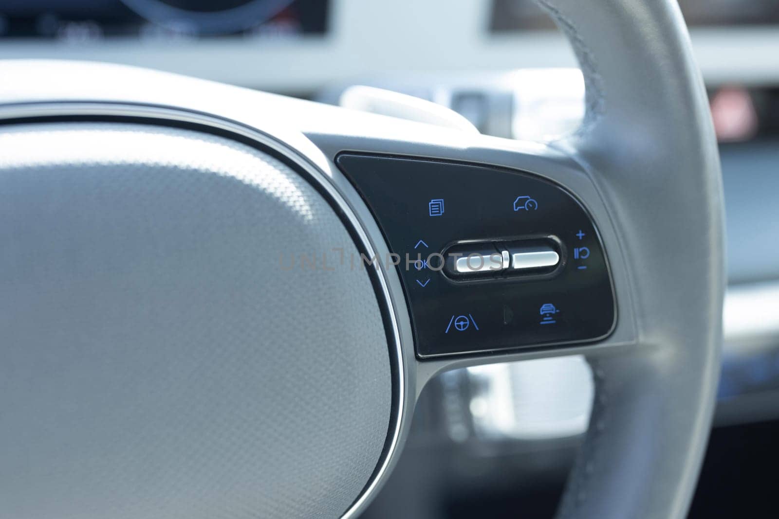 Close up of steering wheel of a new electric vehicle. Electric car control devices. Cruise control buttons, speed limitation, car's signal.