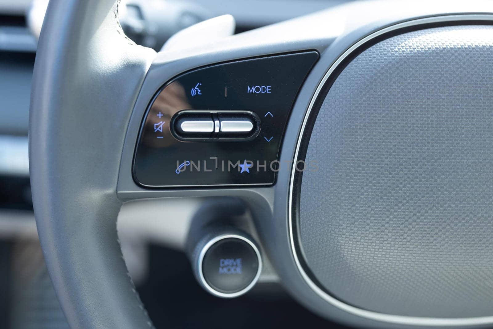 Close-up view of car interior. View of steering wheel of car control music. Volume button of car radio on steering wheel. Turns up the volume of the music in the car. Drive mode.