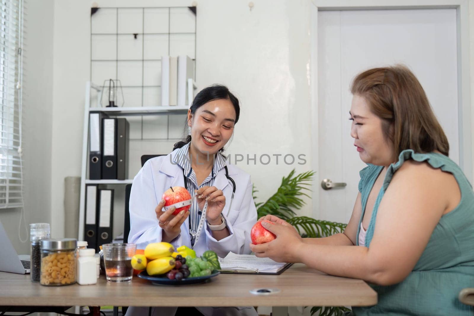 The nutritionist interacts warmly with the patient, discussing the benefit of healthy foods while showcasing apples and other fruits as part of a balanced diet.