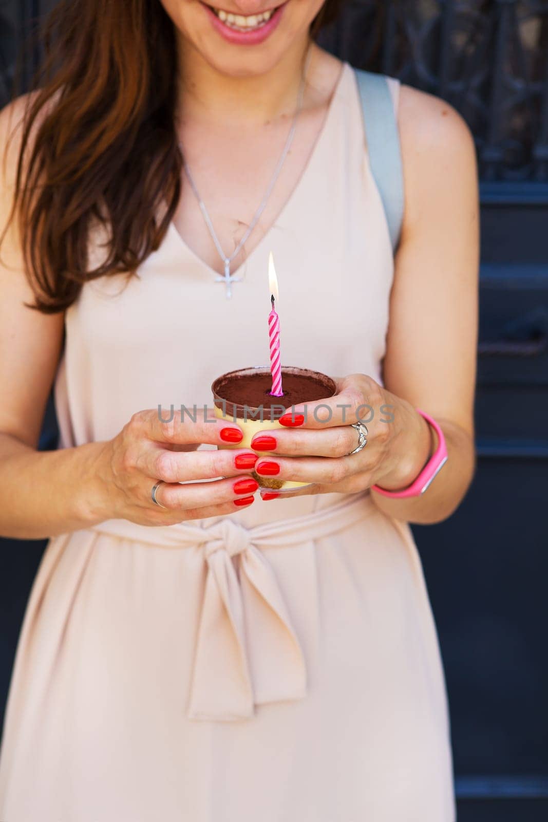a girl with a cake and a candle is standing near the door.
