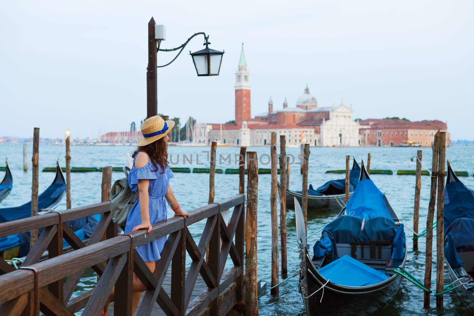 Beautiful sunny Venice, the girl is standing on the bridge near the gondola.