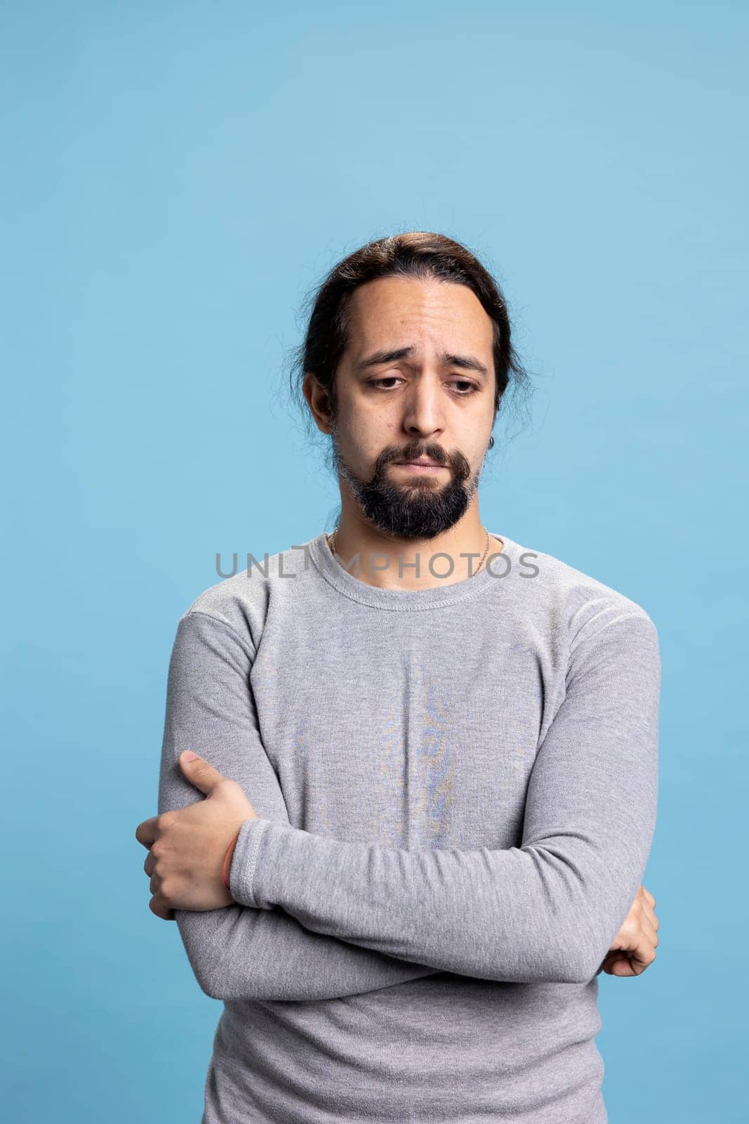 Depressed anxious adult dealing with low self esteem against blue background, whining and being in an emotional crisis. Melancholic person with distress and desolation, disappointed guy.