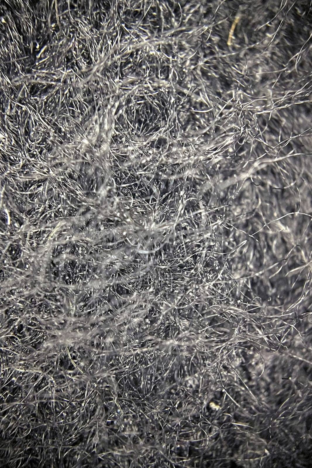 Close-up view of fabric fibers under a microscope, revealing intricate texture and structural complexity.