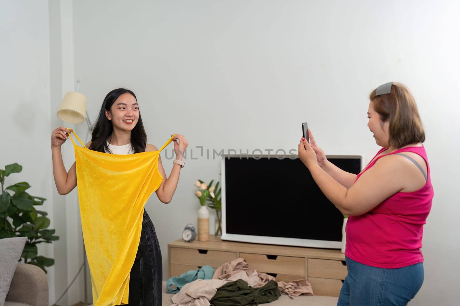 Captured moments of joy as a woman models a striking yellow dress while her friend snaps photos to highlight their unforgettable fun.