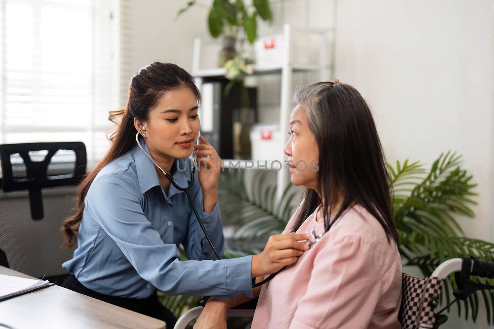 A healthcare professional listens to an elderly patients heartbeat with a stethoscope, emphasizing compassion and attentiveness in a home healthcare setting.