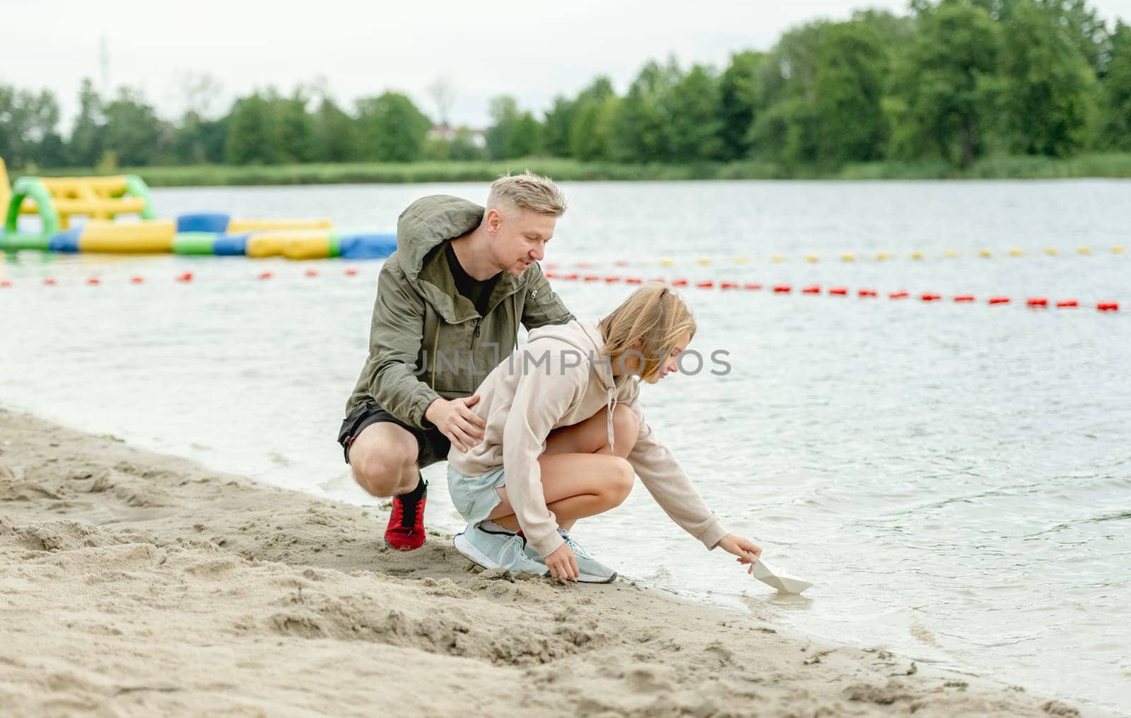 Dad And Daughter Launch Paper Boat In River