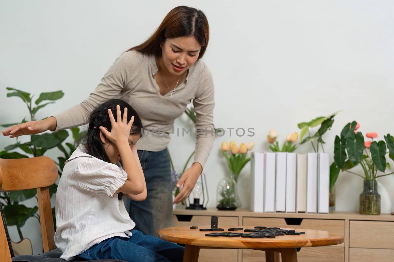 In a nurturing home environment, a mother reassures her daughter amidst a playful moment, encouraging learning from challenges during their game.