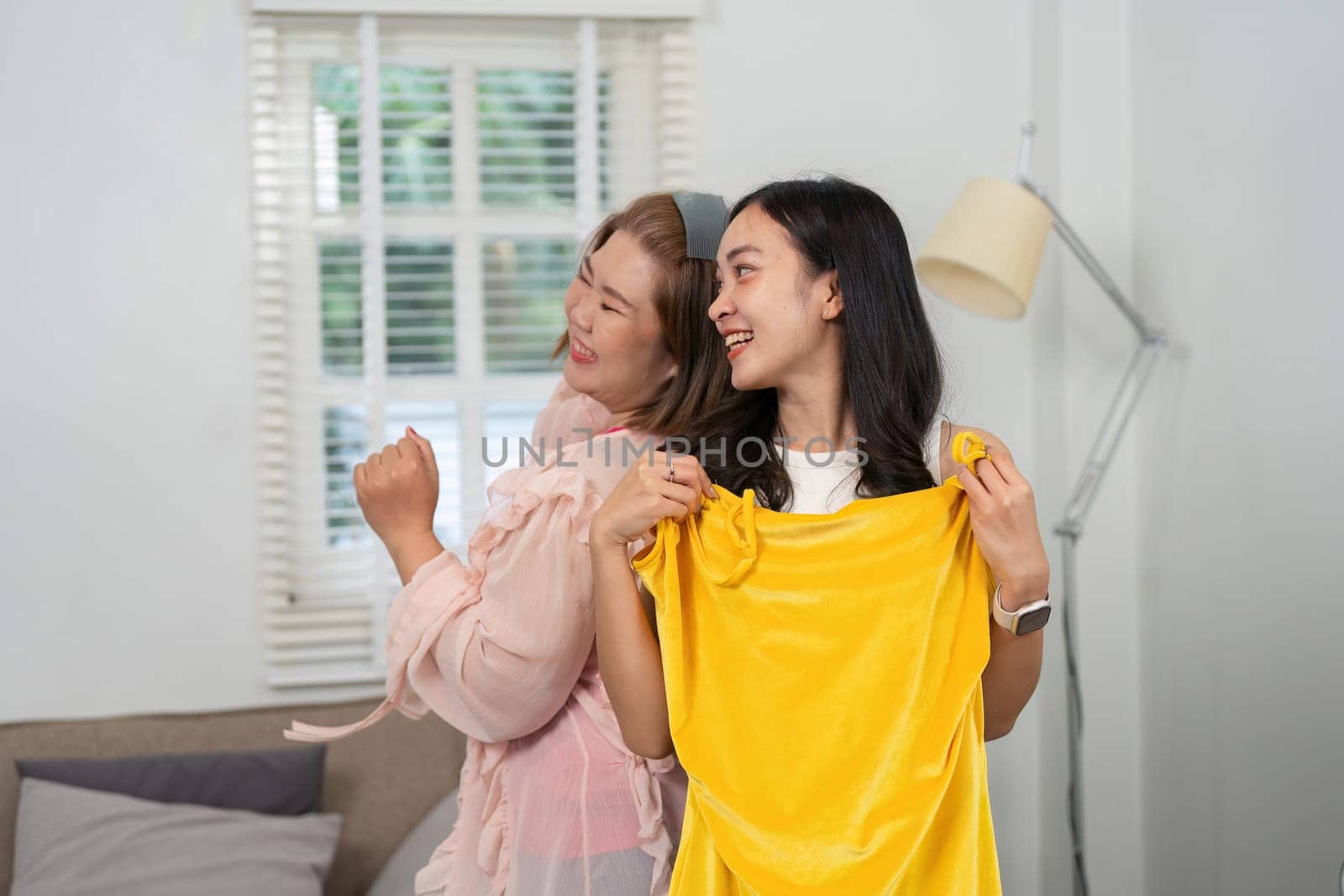 Two friends excitedly present their outfit choices in a lively atmosphere, exploring colors and styles with laughter and genuine camaraderie.