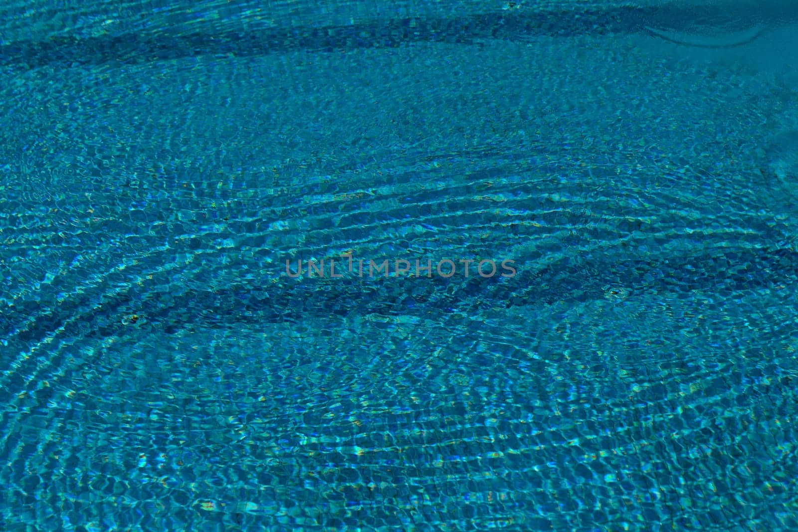 Bright turquoise water dances under the sun, creating shimmering ripples. This tranquil setting invites relaxation on a warm summer afternoon, perfect for enjoying nature's beauty.