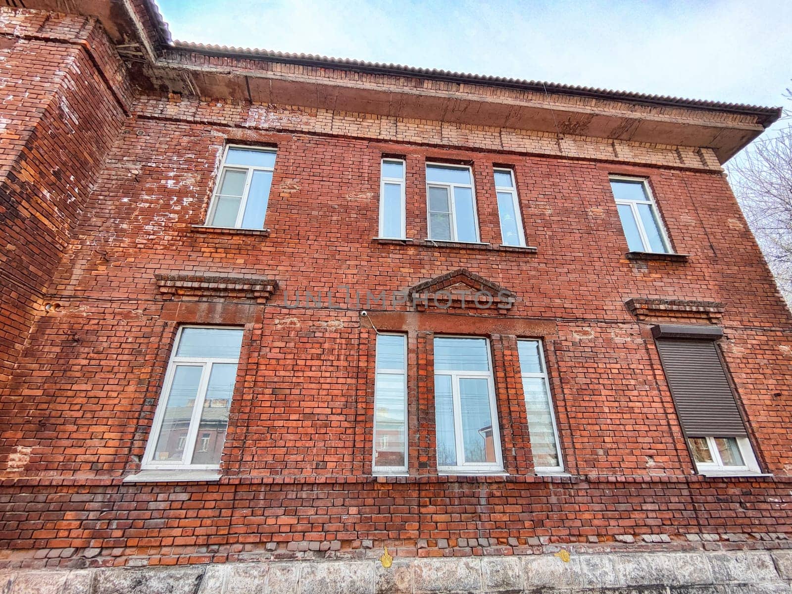 The weathered brick structure features numerous windows and an intriguing facade, located in an urban environment under a clear sky.