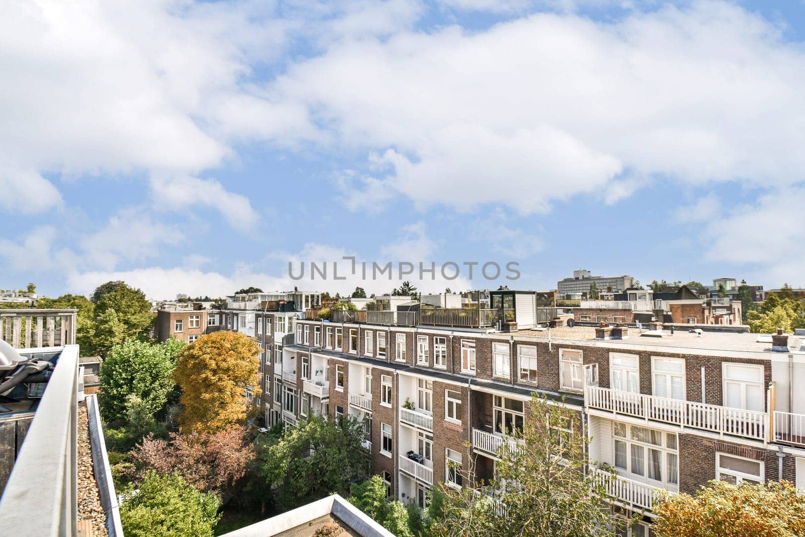 A vibrant urban scene showcasing residential buildings amid lush trees under a blue sky with fluffy clouds, illustrating the harmony of nature and architecture.