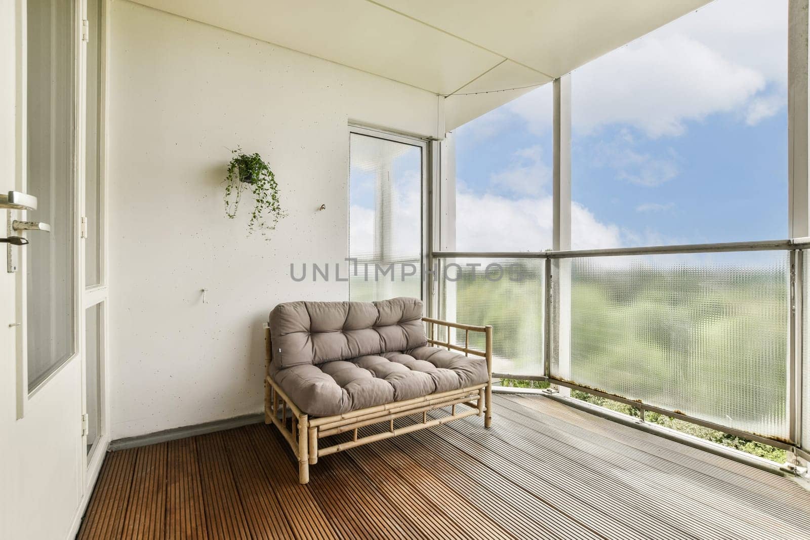 A serene balcony featuring a comfortable seating area surrounded by glass, offering a view of nature and a calm atmosphere.