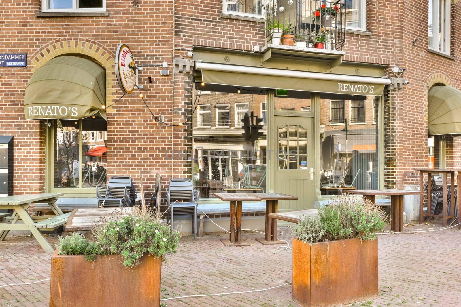 A delightful outdoor cafe featuring cozy seating and vibrant plants, set against a backdrop of historic brick architecture. Perfect for leisurely dining and socializing.